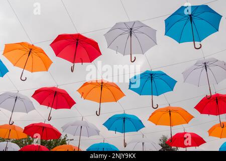 Bunte Regenschirme hängen beim Outdoor-Festival am bewölkten Himmel Stockfoto