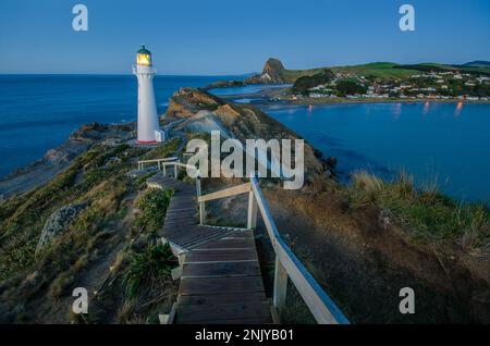 Von oben über einer alten hölzernen Treppe, die zum Castlepoint Lighthouse führt, das sich auf einer grünen Klippe in der Nähe des ruhigen, endlosen Meeres in Neuseeland befindet Stockfoto