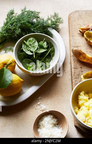 Hoher Winkel von köstlichem frischen grünen Spinat in der Schüssel neben Zitronen und Kartoffelpüree für die Zubereitung von Gnocchi Stockfoto