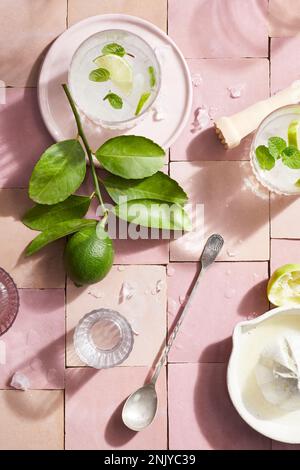 Blick von oben auf frischen Mojito-Cocktail mit Limettenscheiben und Minze auf pinkfarbenen Fliesen Stockfoto