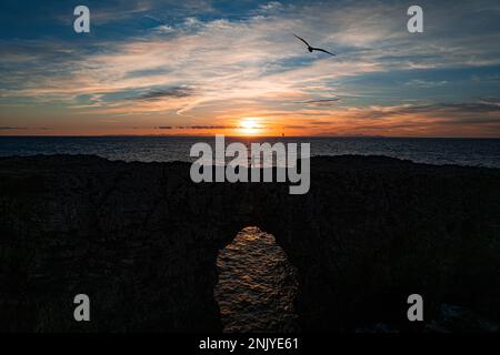 Atemberaubender Blick auf die Silhouette auf der felsigen Brücke Pont den Gil mit einem Loch über dem Meer in der Gemeinde Ciutadella auf der Insel Menorca Stockfoto