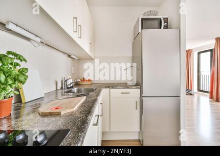 Innendesign einer hellen Küche mit Schränken und Schränken in der Nähe des Kühlschranks in einem modernen Apartment Stockfoto