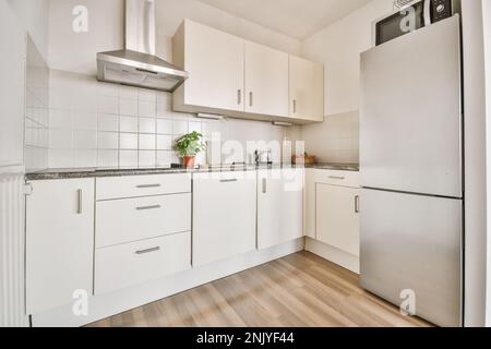 Innendesign einer hellen Küche mit Schränken und Schränken in der Nähe des Kühlschranks in einem modernen Apartment Stockfoto