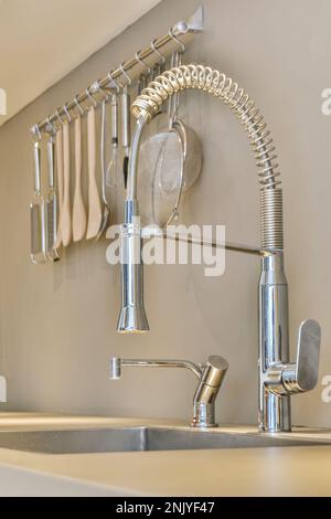 Zeitgenössisches Innendesign der Küche mit langem, hohem Wasserhahn zum Geschirrspülen und kurzem Wasserhahn zum Trinken von Chromwasser im Waschbecken in der Nähe einer hängenden Küche Stockfoto