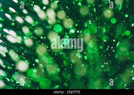 Abstrakte Bokeh-Kulisse mit glänzenden grünen Glitzereffekten und hellen, leuchtenden Lichtern im Dunkeln Stockfoto