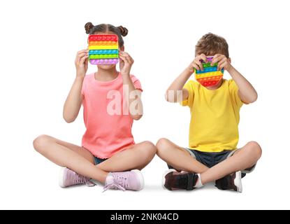 Kinder mit Pop-IT-Spielzeugen auf weißem Hintergrund Stockfoto