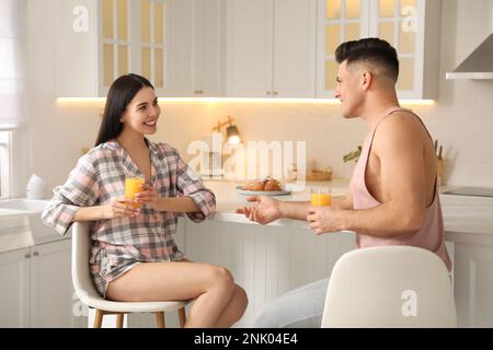 Glückliches Paar mit Schlafanzug beim Frühstück am Tisch in der Küche Stockfoto