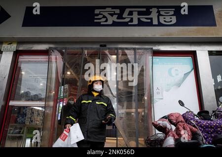 Ein Bote verlässt einen Carrefour-Laden in Wuhan. Carrefour trat im Jahr 1995 in den chinesischen Markt ein und expandierte sehr schnell, um einen großen Marktanteil zu sichern. Die Einnahmen nahmen jedoch mit zunehmender Konkurrenz ab. Im Jahr 2019 verkaufte der französische Einzelhändler rund 80 % seines „verlustbringenden“ Geschäftsbereichs in China für 4,8 Mrd. CNY an das in Jiangsu ansässige Unternehmen „Suning“, was zu diesem Zeitpunkt 699 Mio. USD entsprach. In diesem Monat haben Berichte über Engpässe in den zahlreichen lokalen Carrefour-Filialen die Aufmerksamkeit der Kunden erregt. Mehrere Leute begannen sich zu beschweren, dass sie nicht in der Lage waren, t zu verwenden Stockfoto