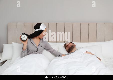 Emotionale Frau, die einen Mann im Schlafzimmer aufwacht. Das Konzept der Verspätung Stockfoto