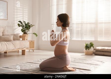 Junge schwangere Yoga zu Hause Stockfoto