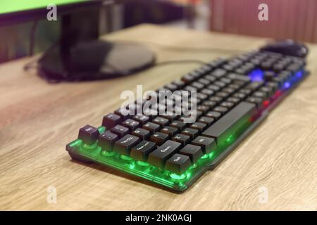 Moderne RGB-Tastatur auf Holztisch im Innenbereich, Nahaufnahme Stockfoto