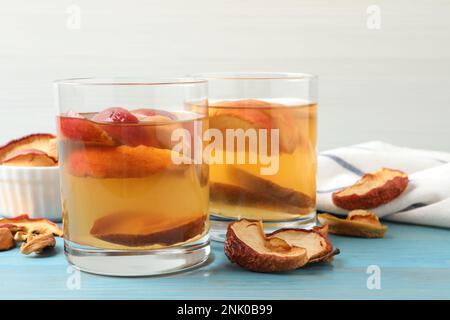 Köstliches Kompott mit getrockneten Apfelscheiben auf einem hellblauen Holztisch Stockfoto