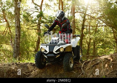 Mann, der ein modernes Quad im Wald fährt. Extremsport Stockfoto