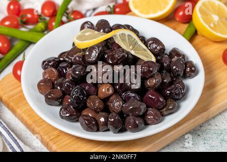 Schwarze Oliven. Oliven auf einem hölzernen Servierbrett. Schließen Stockfoto