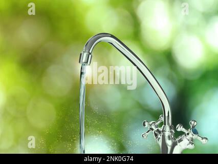 Wasser fließt an sonnigen Tagen aus dem Wasserhahn, Bokeh-Effekt Stockfoto