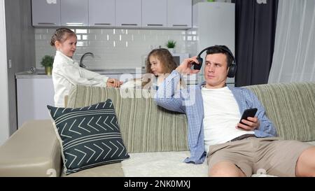 Vater spielt Spiele und hört Musik gegen Kinderkämpfe Stockfoto