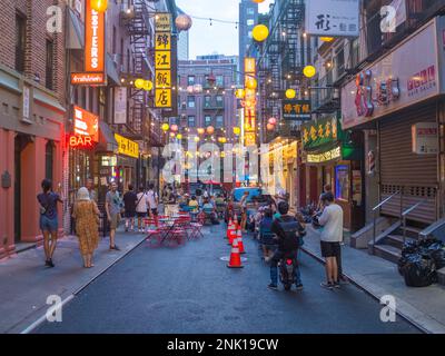New York City, USA - 21. August 2022: Eine Straße in der Chinatown von New York City bei Sonnenaufgang mit Lichtern und Laternen, die eingeschaltet sind und einige Leute Stockfoto