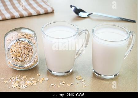 Hafermilch in Glasbechern mit trockenem Hafer in einer Schüssel Stockfoto