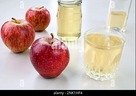Apfelessig in einem Glasbecher mit Äpfeln im Hintergrund Stockfoto