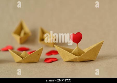 Origami Recyclingpapierboot mit Herz führt eine Gruppe von Booten - Konzept von Liebe, Teamwork und Solidarität Stockfoto