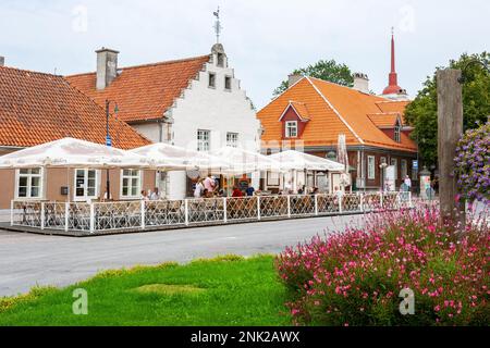 Die Menschen sitzen auf der Sommerterrasse vor historischen Gebäuden in der Altstadt von Kuressaare. Saaremaa, Estland Stockfoto