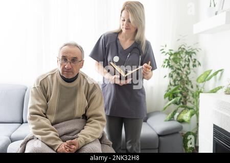 Fürsorgliche Krankenschwester spricht mit altem Patienten hält seine Hand sitzen im Wohnzimmer bei Homecare Besuch bieten psychologische Unterstützung zuhören klagt Empathie zeigen Stockfoto