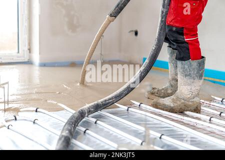 Aufbringung von Beton auf dem Boden bei Fußbodenheizungen Stockfoto