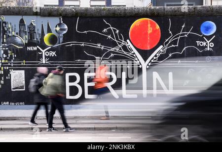 Berlin, Deutschland. 21. Februar 2023. Touristen gehen an einem Wandgemälde in der Eastside Gallery vorbei. Die Tourismusindustrie in Berlin möchte sich mehr auf hochwertige Reisen konzentrieren, um sich nach der Corona-Pandemie zu erholen und die Hauptstadt entsprechend zu fördern. (An dpa 'Tourismusunternehmen: Will keine Junggesellenabschiede anziehen') Kredit: Bernd von Jutrczenka/dpa/Alamy Live News Stockfoto