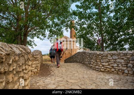 Pilger gehen über eine Steinbrücke, die zur Ermita de la Virgen del Puente führt, einer Kapelle auf dem Jakobsweg in der Nähe von Sahagun Stockfoto