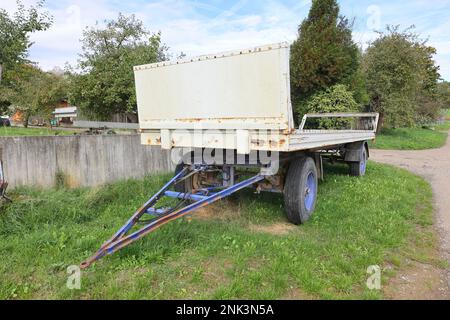 Weißer Anhänger für Heuballen steht auf einer unbefestigten Straße Stockfoto