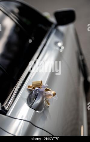 Dekorationen und Details am Auto für das goldene Hochzeitsband am Türgriff des weißen, modernen Autos kleine Schärfentiefe Stockfoto