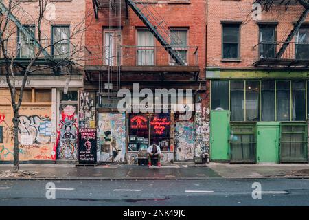 New York, USA - 25. November 2022: Fassade des Overthrow Boxing Clubs in der Bleecker Street, einer der berühmtesten Straßen der Stadt. Ein Mann macht eine Pause Stockfoto