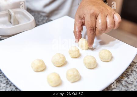 Frauenhände bereiten Mehlbällchen für die Fanesca vor Stockfoto