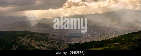 Panoramablick auf Medellin City Antioquia Kolumbien mit den Bergen der anden im Hintergrund. Die Sonne scheint unter den Wolken und leuchtet auf Stockfoto