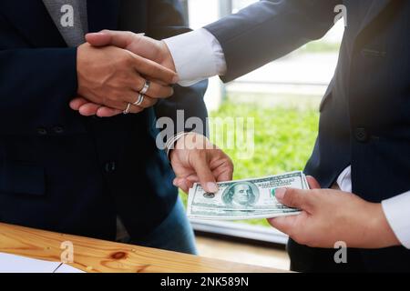 Geschäftsmann-Handschlag und Dollarscheine in den Händen. Unehrliches Betrügen im Geschäft illegales Geld, Bestechung und Korruption Konzept. Bankkunden kommen Stockfoto