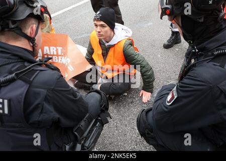 Hamburg, Deutschland. 23. Februar 2023. Die Aktivisten der Umweltgruppe "Last Generation" haben sich an der Gorch-Fock-Wall am Stephansplatz festgeklemmt und möchten auf die Einhaltung der Klimaziele aufmerksam machen. Polizisten sprechen mit den Aktivisten. Kredit: Bodo Marks/Bodo Marks/dpa/Alamy Live News Stockfoto