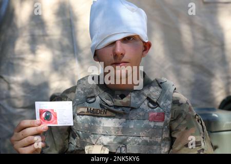 USA Alexander Maiden, ein Multichannel Transmission Systems Operator-Maintainer der Charlie Company, 237. Stützbataillon, hält seine Verletzungskarte hoch, die eine simulierte Augenwunde während einer Trainingsübung in Camp Grayling, Michigan, am 11. August 2022 zeigt. Die Jungfrau arbeitete als simuliertes Opfer während der medizinischen Trainingsveranstaltung, die den Soldaten von C Co geholfen hat, sich besser auf ähnliche Situationen vorzubereiten, die sie im Einsatz treffen könnten. Stockfoto