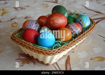 Nahaufnahme eines Webkorbs mit bunten gefärbten Eiern für die traditionelle Osterfeier in Bulgarien im april. Horizontales Bild mit selektivem FO Stockfoto