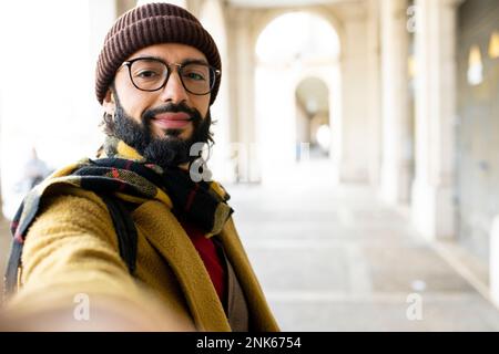 Glücklicher Mann, der Selfie auf der Straße machte - männlicher Tourist, der Spaß im Urlaub hat - lächelnder Kerl, der draußen in die Kamera schaut - Fokus auf die Augen Stockfoto