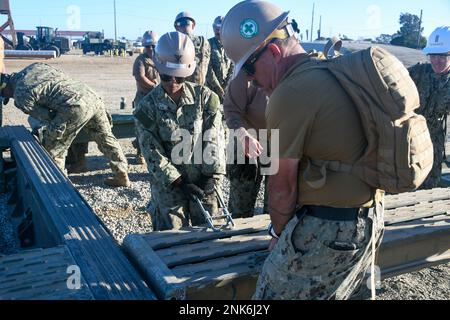 PORT HUENEME, Kalifornien (11. August 2022) Seebäume, die dem mobilen Marinebataillon (NMCB) 18 zugeteilt sind, befestigen während der Feldübungsübung (FTX) der NMCB 18 Rampen an einem Brückenprojekt. Die FTX dient der Analyse der Baukapazitäten eines Bataillons, der Expeditionslogistik und der Kampfoperationen zur Unterstützung größerer Kampfeinsätze, der Katastrophenbewältigung und der humanitären Hilfe. Stockfoto