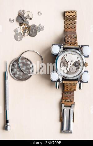 Blick über die alte Armbanduhr mit rostigem Armband auf einem Holztisch in der Uhrmacherwerkstatt Stockfoto