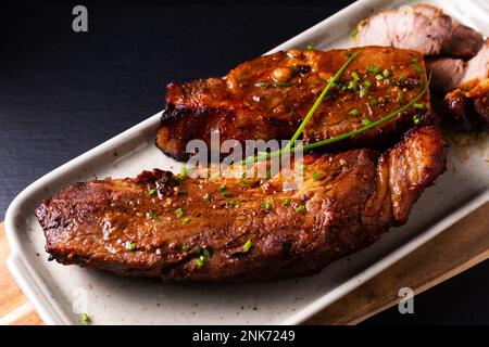 Speisekonzept hausgemachtes Char siu gegrilltes Schweinefleisch im kantonesischen Stil auf schwarzem Steinhintergrund mit Kopierbereich Stockfoto