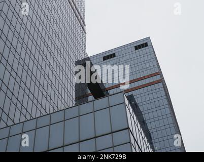 Gläserne Gebäude mit Wolkenkratzern und grauem Himmel an bedeckten Tagen Stockfoto