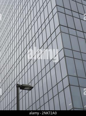 Straßenlaterne und Wolkenkratzer-Glaswand im Hintergrund Stockfoto