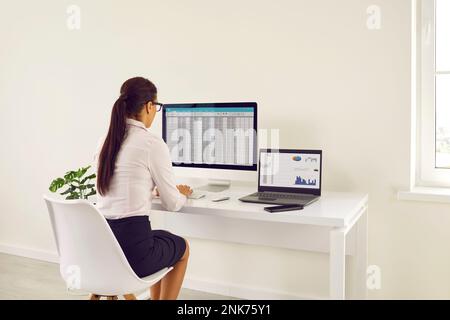 Weibliche Analystin, die mit Rechnungscodes und Tabellenkalkulationsdaten im Büro arbeitet Stockfoto