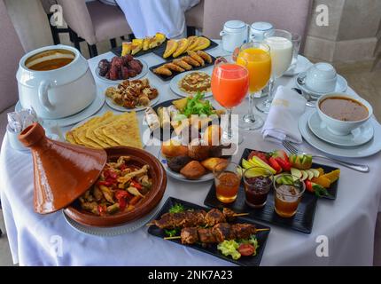 Marokkanisches Frühstück im Ramadan. Harira-Suppe. Datteln, Tee, Säfte und verschiedene Süßigkeiten Stockfoto