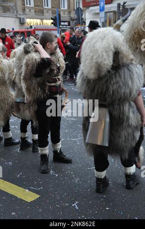 Rijeka, Kroatien, 19. Februar 2023. Ringer-Glocken, eine traditionelle, maskierte Gruppe von Kindern und Erwachsenen, bedeckt mit Schaffell- und Tiermasken, läutet mit Stockfoto