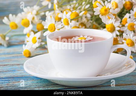 Kamillenblüten für die Teezubereitung und ein Strauß Kamillenblüten aus Matricaria auf Holzhintergrund. Stockfoto