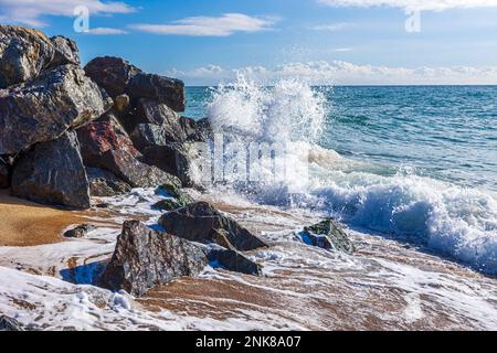 Stürmische Meereswellen, die auf die Felsen an einem Sandstrand an der Costa Brava, Katalonien, Spanien treffen. Stockfoto
