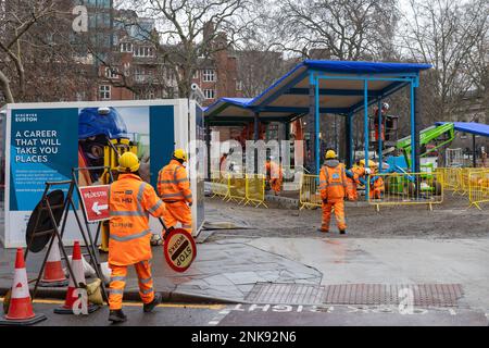 London, Großbritannien. 22. Februar 2023. Arbeiter, die Warnkleidung und Helme tragen, betreten einen HS2 erbauten Standort in den Euston Square Gardens. In den Euston Square Gardens werden derzeit mehrere weitere Bäume für das Hochgeschwindigkeitsbahnprojekt gefällt. Der Schatzkanzler Jeremy Hunt teilte am 27. Januar mit, dass das Hochgeschwindigkeitsbahnprojekt Euston wie ursprünglich geplant erreichen wird, nachdem Zeitungsberichte berichtet hatten, dass die Strecke am Old Oak Common enden könnte. Kredit: Mark Kerrison/Alamy Live News Stockfoto